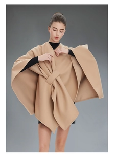 Detail of the camel wool cape showing the cross-front design and elegant drapery