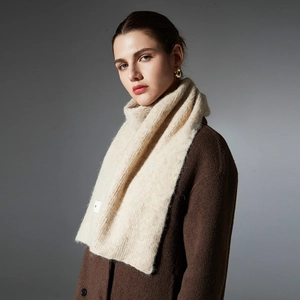 Premium beige knit wool scarf for women featuring a minimalist sewn brand label and soft texture