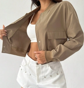 Detail of khaki cropped bomber jacket featuring utility flap pocket and metal snap buttons