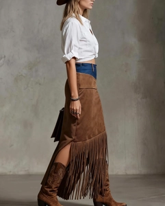 Macro shot of faux suede skirt featuring long fringe hem and denim patchwork detail