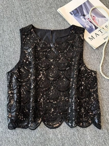 Macro detail of black sleeveless top with scalloped sequin patterns and pearlescent shine