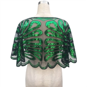 Détail de la cape en maille noire avec broderies à paillettes vertes et bords festonnés