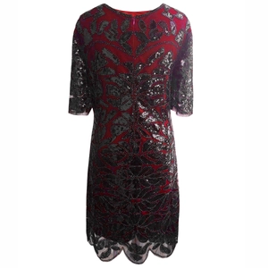 Detail of red mesh dress with black sequin floral patterns and scalloped hemline
