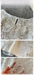Detail of white sequin lace top featuring pearl button closure and shimmering mesh fabric