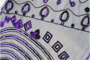 Détail macro de broderie paillettes violettes et perles argentées sur châle de soirée