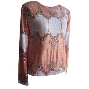 Close-up of coral pink and white sequined floral patterns on long-sleeved evening blouse