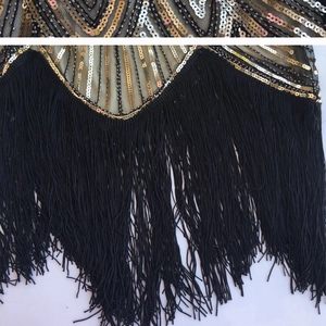Detail of 1920s dress with gold and silver sequin patterns and black fringe tassels