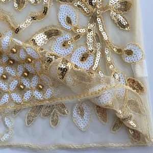 Detailansicht des Netzstoffs mit goldenen Pailletten und weißer Perlenbestickung