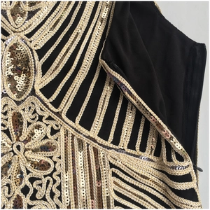 Detail of 1920s vintage dress with gold sequins and intricate embroidery on black mesh