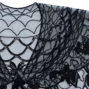 Détail de sequins noirs avec broderies papillon et étoile sur cape des années 20