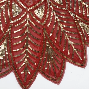 Detail of red mesh fabric with golden sequins in scalloped feather patterns for evening gowns