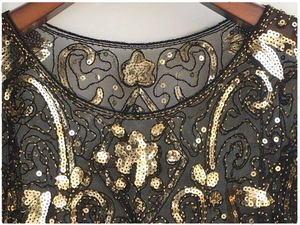 Detailed view of 1920s vintage shawl featuring gold sequins on black mesh fabric