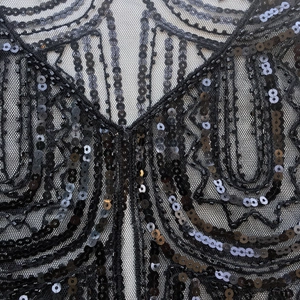 Detailed close-up of intricate black sequins and beadwork on a vintage mesh shawl