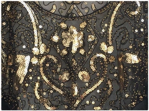 Detail of 1920s vintage evening shawl with gold sequins on black mesh fabric