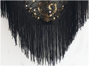 Detailed macro view of black mesh shawl with golden sequins and long fringes