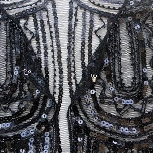 Detail of 1920s mesh shawl showing intricate black sequins and metal hook closure