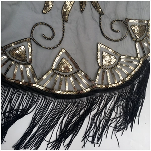Detail of evening shawl featuring gold sequins, mesh fabric and long black silk tassels