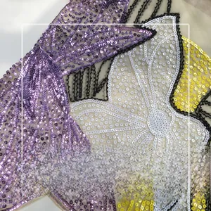 Detailed macro view of sheer beige mesh fabric with intricate floral sequin embroidery
