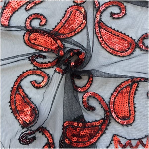 Close-up of black mesh lace fabric with intricate red paisley sequin patterns
