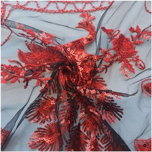Close-up of red phoenix embroidery and shimmering sequins on black sheer mesh fabric