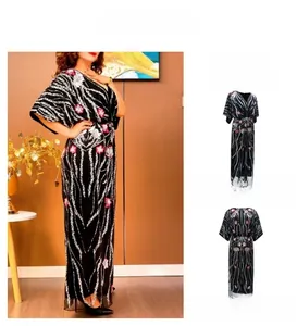 Détail d'une robe longue élégante à col en V avec broderie florale, sequins et manches chauve-souris