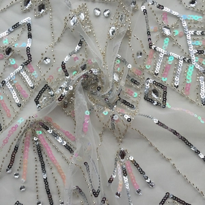 Detailed close-up of handmade sequin and bead embroidery on white tulle fabric