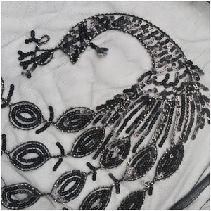 Détail de sequins paon cousus main et broderies sur tissu en maille noire de luxe