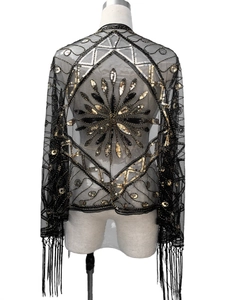 Close-up of vintage 1920s black mesh shawl featuring gold and silver sequins and long tassels