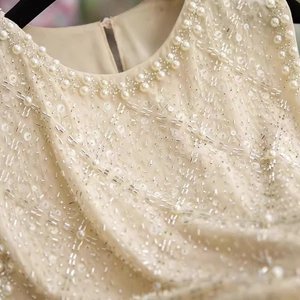 Détail de la broderie de paillettes et perles sur un haut en mousseline beige