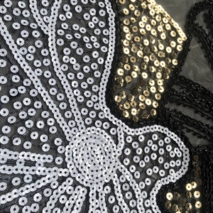 Close-up of intricate silver and gold sequins embroidered on black mesh long sleeve top