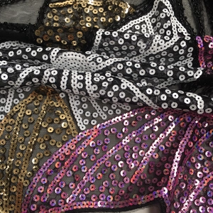 Macro detail of intricate sequins and embroidery on sheer black lace mesh fabric