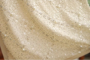 Détail macro de broderies de perles et paillettes sur tissu en mousseline beige