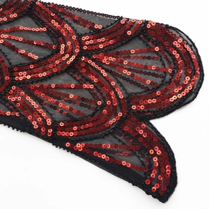Detail shot of vintage red sequins on black mesh fabric with elegant scroll patterns
