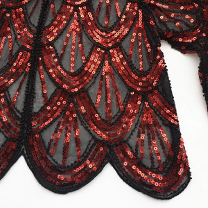 Detailed macro view of 1920s evening shawl with red sequins on black mesh fabric