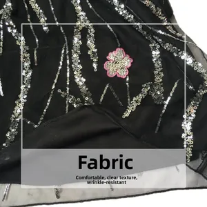 Detail of black mesh dress with silver sequins, pink flower embroidery, and clear texture
