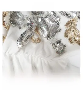 Detail of elegant V-neck gown with intricate gold and silver sequins on white mesh fabric
