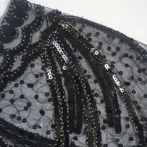 Close-up of black mesh cape with intricate sequins, bead embroidery and wave patterns