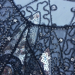 Detailed view of black 1920s vintage dress mesh fabric with silver sequins and beadwork