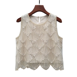 Détail du gilet blanc orné de paillettes, perles et broderies de vagues