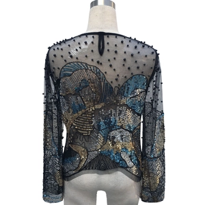 Vista posteriore di un top in mesh a maniche lunghe con paillettes pesanti e decori di perle