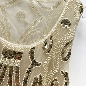 Sequin tank top with beaded mesh detailing and elegant glittery patterns on beige fabric