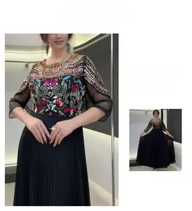 Détails de broderie florale et de perles sur une robe longue plissée en mousseline noire