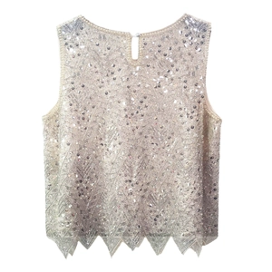 Detail of beaded sequin vest with geometric patterns and pearl neckline accent