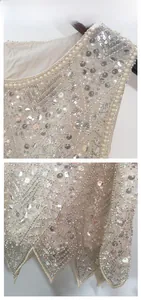 Close-up of intricate hand-stitched sequins and pearl beadwork on champagne vest