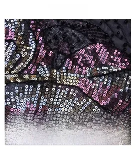 Macro di un ricamo intricato di paillettes su rete nera con perline e riflessi metallici