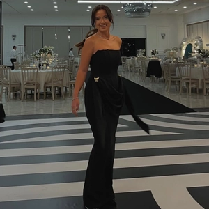Robe de soirée noire sans bretelles avec drapé latéral et boucle papillon dorée