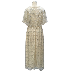 Detailed back view of a champagne sequined evening gown with scalloped hem and shawl detail