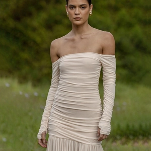Détails d'une robe en maille crème avec plis verticaux et manches à passe-pouces