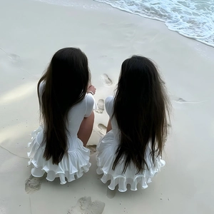 Dettaglio dell'abito mini bianco a balze in raso di alta qualità ambientato sulla spiaggia