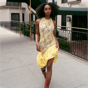 Detail of floral lace texture and ruffled hem on yellow sleeveless sheer dress